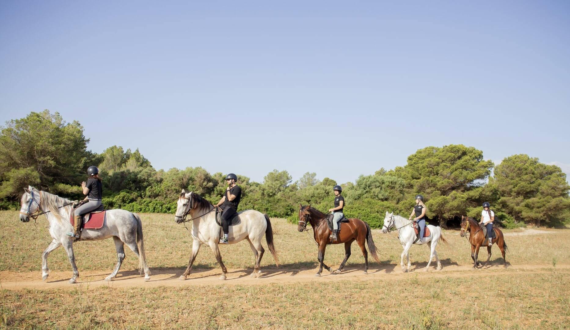 group riding horses on the beach near son baulo mallorca